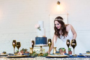 Bride arranges cutlery on gold and navy wedding table at Yorkshire Wedidng Venue