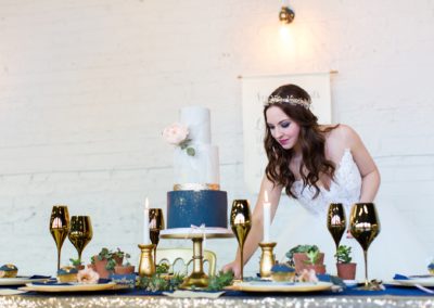 Bride arranges cutlery on gold and navy wedding table at Yorkshire Wedidng Venue