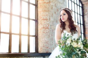 Bride standing by open mill window at River Mills Ballroom